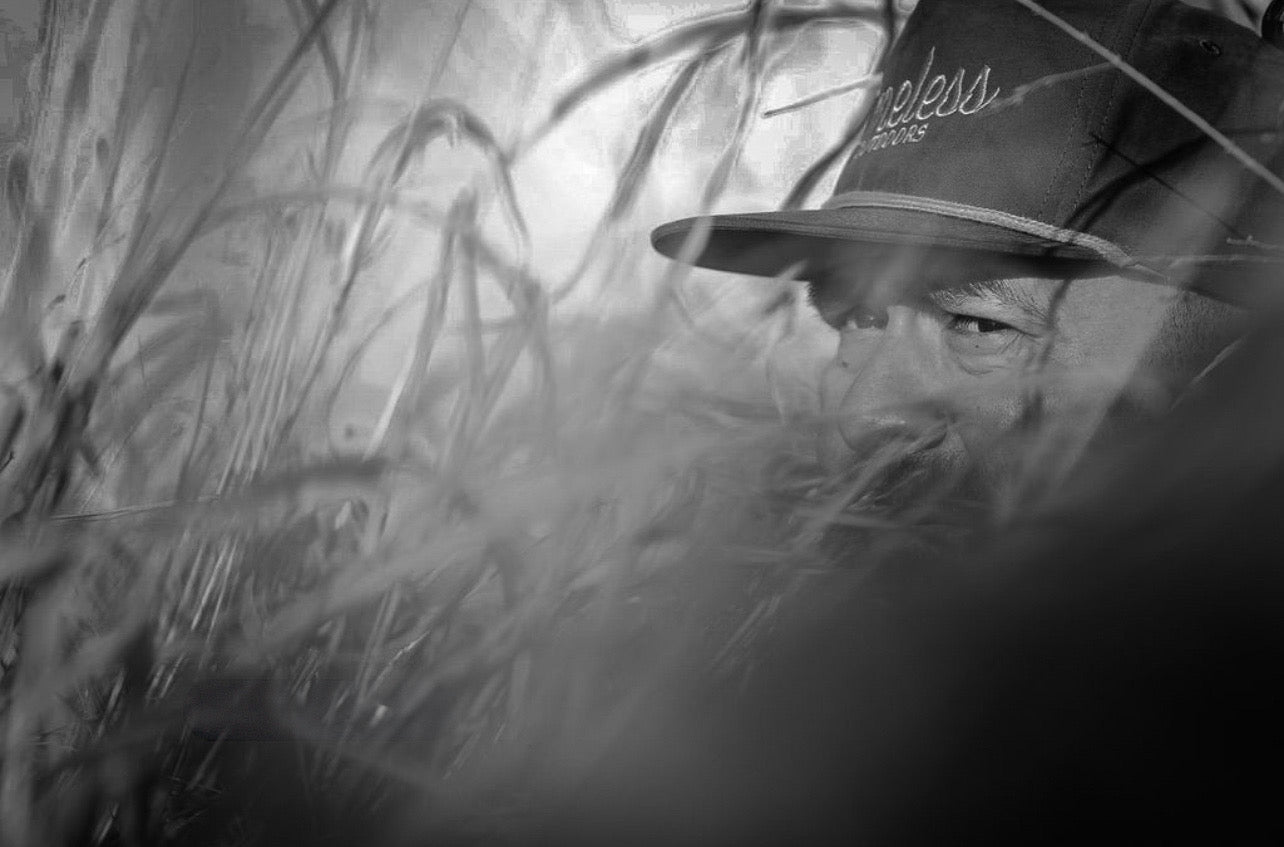 Man in Timeless Outdoors hat sitting in the reeds