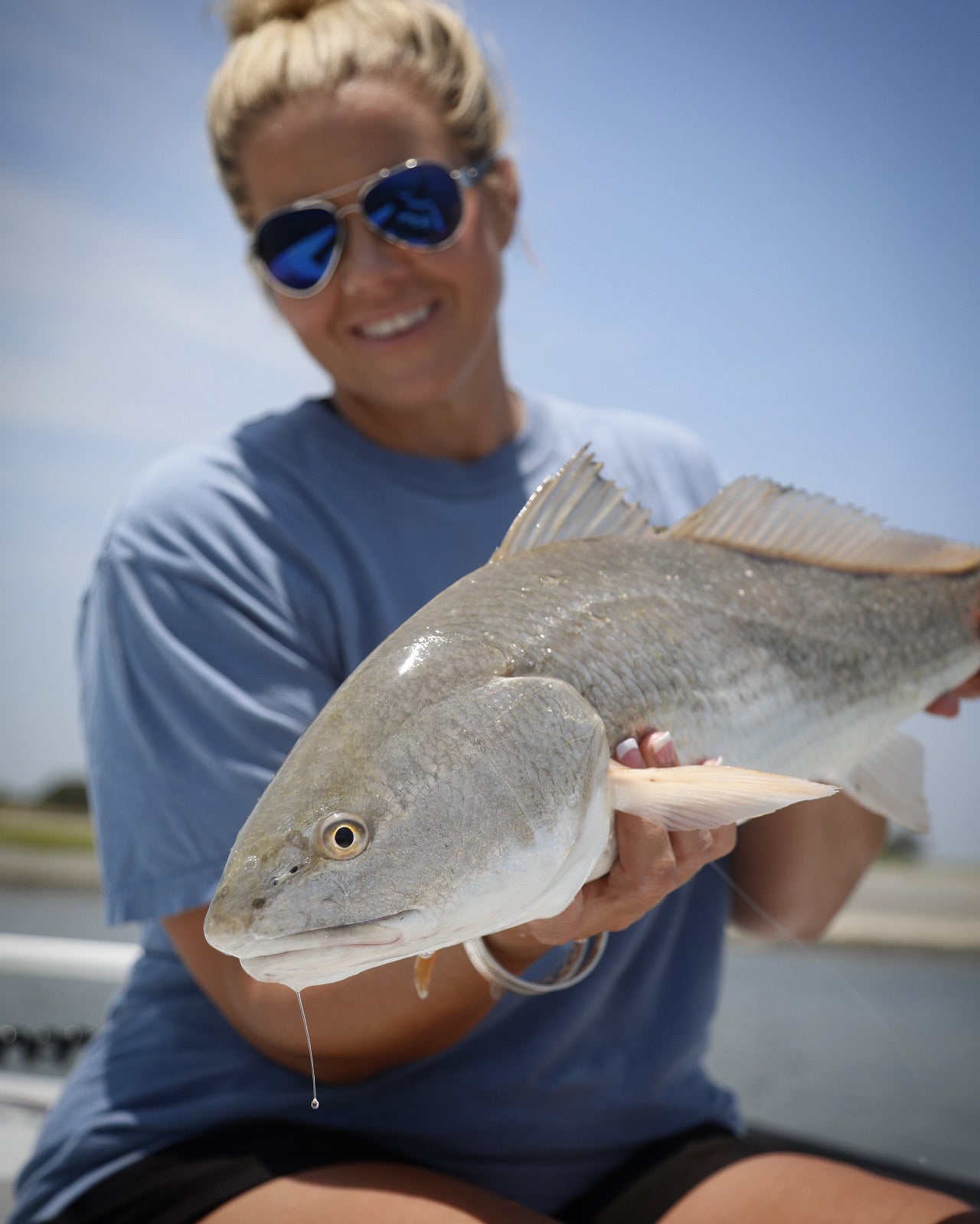 woman holding up a fish she caught