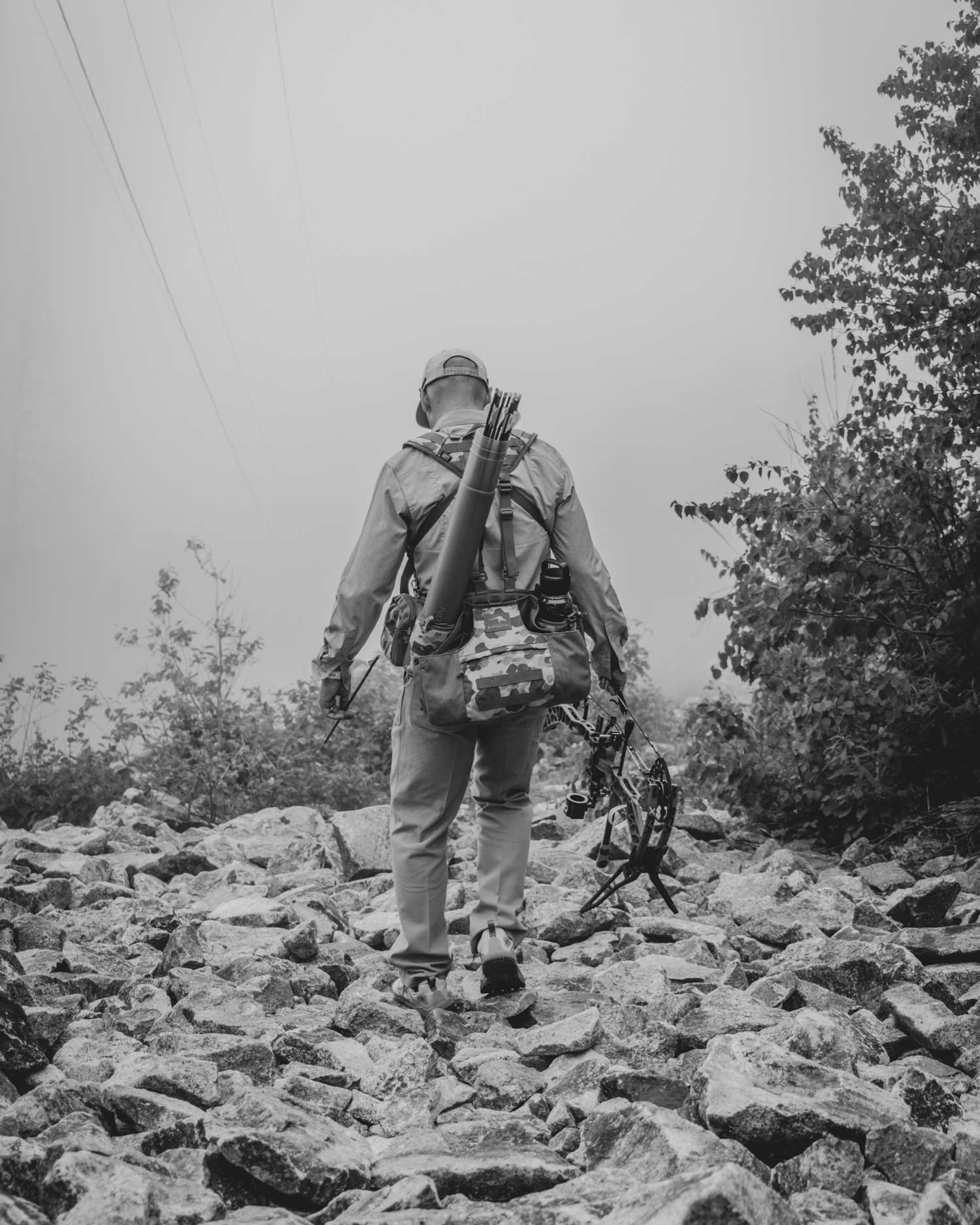 lone hunter carrying his box as he walks over rocks
