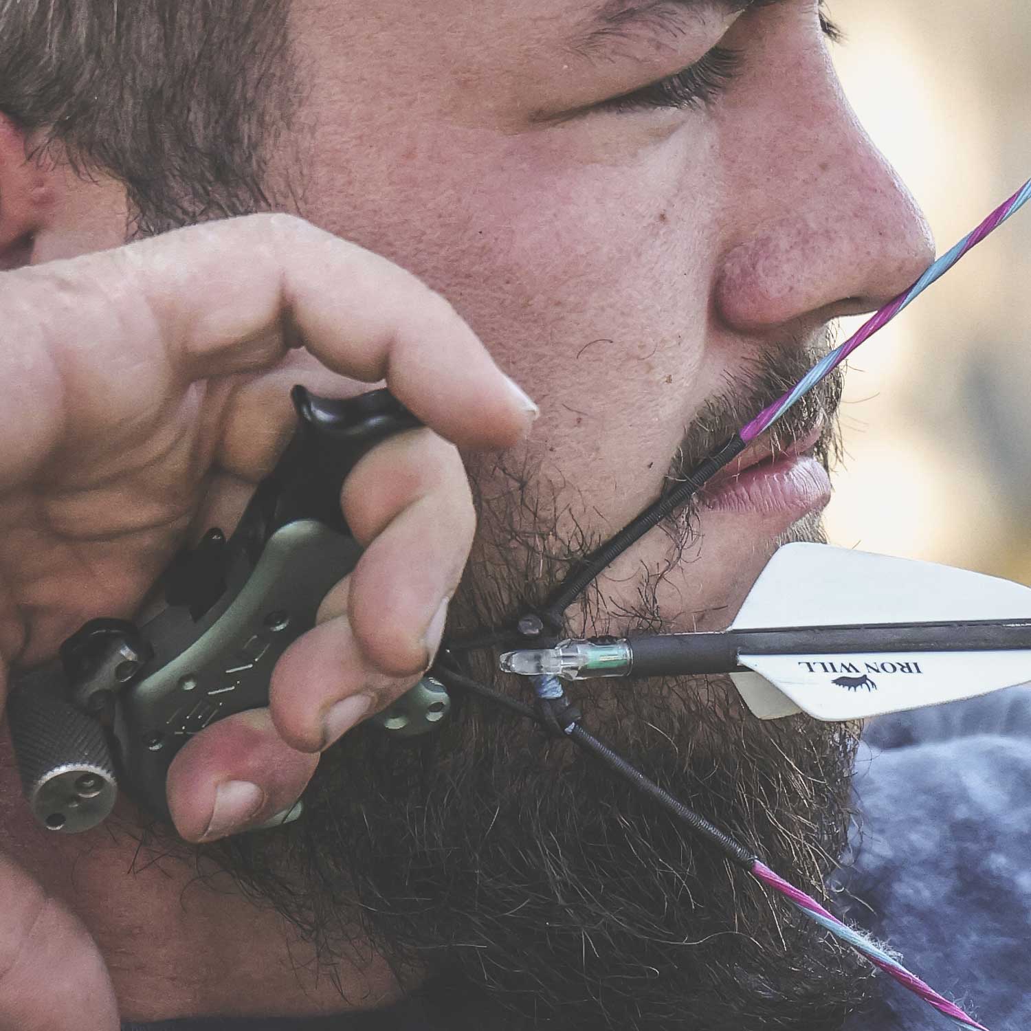 man holding a bow against the side of his face